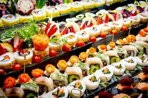 Foto von verschiedenen Sushi-Rollen auf einem Buffet, alle mit verschiedenen Toppings dekoriert.