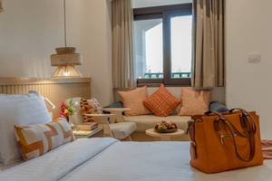 Drei-Ecken-Rihana-Resort-Zimmer mit Bett, Fenster, und Taschen auf dem Bett.