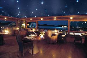 Innenansicht des Restaurants im Elounda Beach Hotel & Villas mit Sternenhimmeldecke und Blick auf den Hafen.