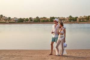 Paar am Strand des Three Corners Rihana Resorts mit Blick auf Wasser und Gebäude