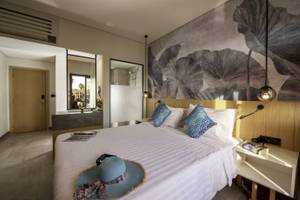 Hotelzimmer im Three Corners Rihana Resort mit Bett, Hut, Büchern und Lampe.