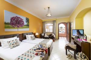 Doppelzimmer im Three Corners Rihana Resort mit zwei Betten, Fernseher und Möbeln.