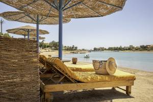 Strandszene im Three Corners Rihana Resort mit Liegen, Sonnenschirmen und einem Blick aufs Wasser.