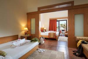 Hotelzimmer im Three Corners Fayrouz Plaza Beach Resort mit zwei Betten, Tisch, Lampen und Balkon.