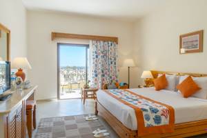 Ein elegantes Zimmer im Three Corners Fayrouz Plaza Beach Resort mit einem großen Bett und einem Balkon mit Meerblick.