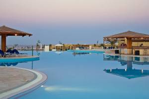 Ein Swimmingpool des Three Corners Fayrouz Plaza Beach Resorts bei Sonnenuntergang.
