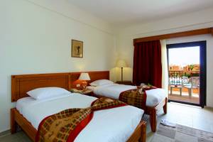 Zwei Betten im Zimmer im Three Corners Fayrouz Plaza Beach Resort mit Blick auf den Balkon.