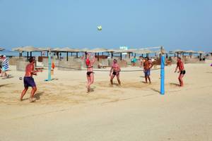 Mehrere Männer spielen Volleyball am Strand des Three Corners Fayrouz Plaza Beach Resort.