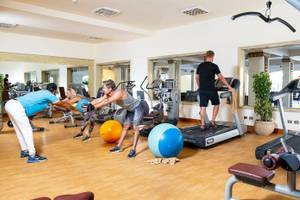 Fitnessstudio im Three Corners Fayrouz Plaza Beach Resort mit Personen, die an Geräten trainieren.