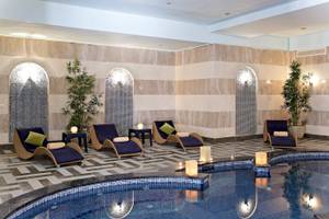 Pool-Bereich im Three Corners Fayrouz Plaza Beach Resort mit Liegen und blauen Kissen.