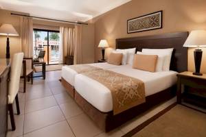 Doppelbett-Zimmer im JAZ Neo Dar El Madina Hotel mit gemusterten Laken, zwei Nachttischen und Lampen.