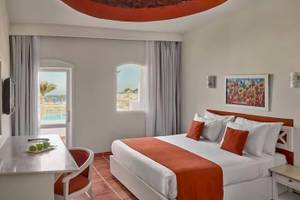 Innenansicht eines Zimmers im Jaz Neo Reef Marsa mit einem Bett, Schreibtisch, Fenster und Meerblick.