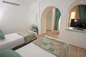 Zwei Doppelbetten mit blauen Kissen in einem eleganten Zimmer des Sunrise Royal Makadi Resorts.