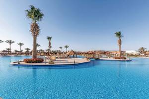 Außenpool des Sunrise Royal Makadi Resorts mit Palmen und Gebäuden im Hintergrund.