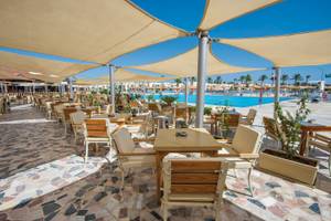 Außenbereich des Sunrise Royal Makadi Resorts mit Tischen, Stühlen und Sonnenschirmen.