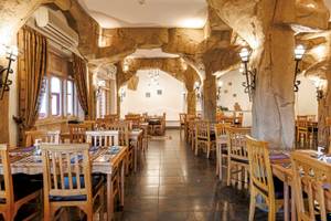 Innenbereich des Restaurants im SUNRISE Royal Makadi Resort mit Holztischen, Stühlen und steinernen Säulen.