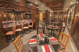 Innenansicht des Restaurants im Sunrise Royal Makadi Resort mit runden Tischen, Stühlen und Holzdesign.