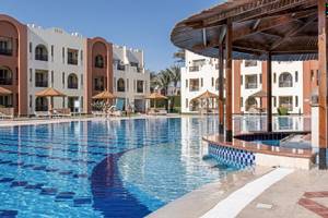 Pool-Bereich des Sunrise Royal Makadi Resorts mit umliegenden Gebäuden und Sonnenschirmen.