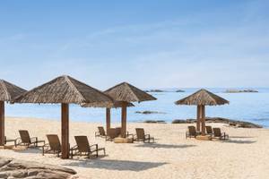 Strand des Wyndham Garden Salalah Mirbat mit Liegen unter Strohdächern