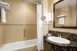 Badezimmer im Wyndham Garden Salalah Mirbat Hotel mit Badewanne, Waschbecken und Spiegel.