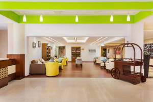 Lobby des Wyndham Garden Salalah Mirbat mit gelben Sesseln und einem Servierwagen