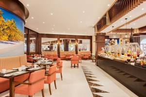 Restaurant des Wyndham Garden Salalah Mirbat Hotels mit orangen Stühlen und Tischen.