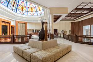 Empfangshalle des Wyndham Garden Salalah Mirbat mit Sitzecke, Vasen und buntem Glasdach