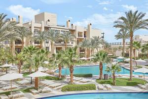 Außenbereich des Steigenberger Aqua Magic Resorts mit Pool, Palmen und Liegestühlen.