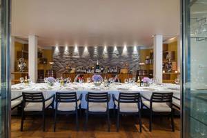 Ein elegantes Esszimmer im One & Only Reethi Rah mit einer langen Tafel, gedeckt für mehrere Personen, und Dekorelementen.