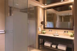 Badezimmer im Anantara The Palm Dubai Resort mit Glasdusche, Waschbecken und Spiegel.
