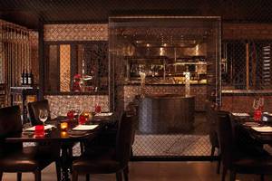 Innenbereich des Restaurants im Anantara The Palm Dubai Resort mit gegrillten Tischen und dunkler Atmosphäre.