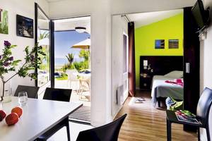 Innenansicht des Belambra Club Golfe de Lozari Hotels mit Wohnbereich, Esstisch und Blick auf die Terrasse.