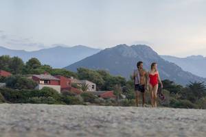 Paar am Strand vor dem Hotel Belambra Club Golfe de Lozari mit Blick auf die Berge
