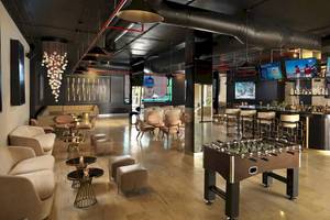 Loungebereich des Melia Caribe Beach Resorts mit Fernsehern, Bar, Fußballtisch und Möbeln.