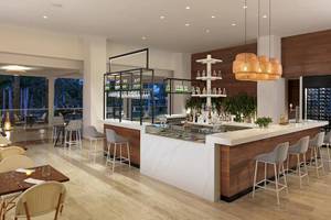 Innenansicht der Bar im Melia Caribe Beach Resort mit Holzboden, weißen Marmortischen und Barhockern.