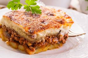 Griechisches Lasagne auf einem weißen Teller mit einer Gabel