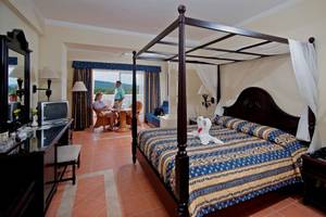 Ein Hotelzimmer im Bahia Principe Grand Jamaica Hotel mit einem Himmelbett und einem Paar, das sich unterhält.