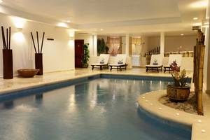 Pool-Loungebereich im Bahia Principe Grand Jamaica mit Loungestühlen und Pflanzen.