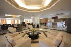 Lobby des Marianna Palace Hotels mit weißen Möbeln, einem zentralen Tisch und einer Rezeption im Hintergrund.