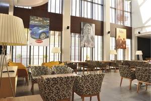 Innenbereich des Cettia Beach Resorts mit Sitzgruppen, Tischen, Lampen und Wandpostern.