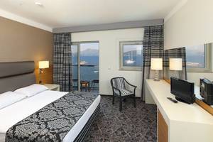 Bettzimmer im Cettia Beach Resort mit Meerblick, modernem Design und bequemen Möbeln.