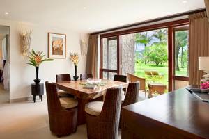 Inneneinrichtung des Kempinski Seychelles Resorts: Esszimmer mit Tisch, Stühlen und Glastüren, die auf eine Rasenfläche führen.