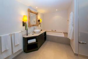 Ein modernes Badezimmer mit Badewanne, Waschbecken und großen Spiegel im Kempinski Seychelles Resort.