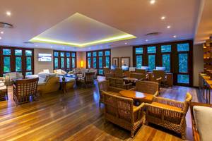 Loungebereich des Kempinski Seychelles Resorts mit Holzboden, modernen Möbeln und großen Fenstern.
