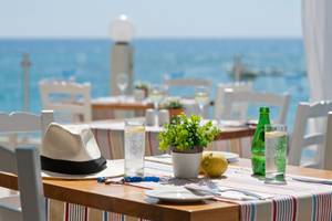 Terrasse des Pernera Beach Hotels mit Blick auf das Meer und einem gedeckten Tisch.