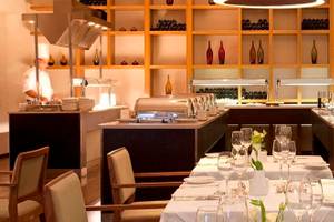 Innenbereich des Alion Beach Hotel Restaurants mit gedeckten Tischen, Geschirr und Köchen hinter einer Theke.