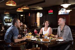 Drei Gäste im Jumeira Rotana Hotel sitzen am Tisch und essen und trinken.