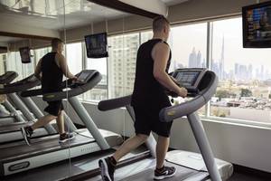 Zwei Männer trainieren auf Laufbändern im Fitnessstudio des Jumeira Rotana Hotels.