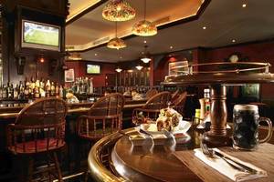 Innenansicht der Bar im Jumeira Rotana Hotel mit Sitzgelegenheiten und Getränken.