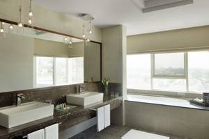 Badezimmer im Jumeira Rotana Hotel mit zwei Waschbecken, Badewanne und Fenstern.